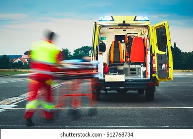 Emergency medical service. Paramedic is pulling stretcher with patient to the ambulance car. - Shutterstock ID 512768734