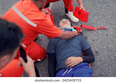 Emergency medical service team is rescuing Asian young manใ The emergency response team is trying to administer first aid to an Asian man who has had an accident on the side of the road. - Powered by Shutterstock