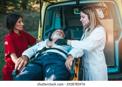 Emergency medical service at work. Paramedic is pulling stretcher with senior man with serious heart attack to the ambulance car. Help on the road. Drivers assistance concept. - Powered by Shutterstock