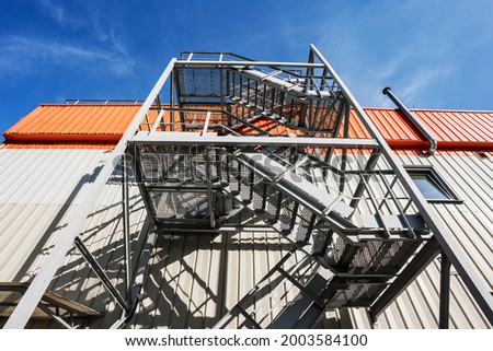 Emergency metal staircase on side wall of industrial or office building outdoor