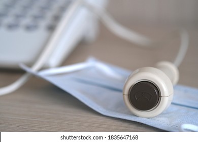 Emergency Nurse Call Equipment With Nurse's Cap Sign On Brown Button (press The Button For Nurse Assistance) On Face Mask On Wooden Table With Landline Telephone On Background. Selective Focus.