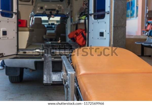 Emergency patient medical trolley with background of\
ambulance with back door\
open