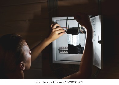 Emergency Power Outage In House. Woman With Flashlight Looks Into Distribution Board. Short Circuit.