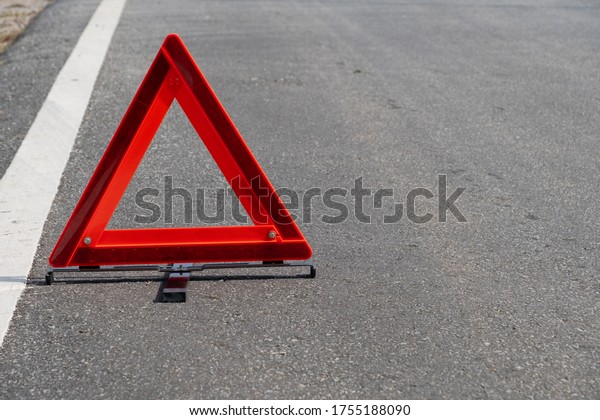 Emergency red warning triangle on the road sign with\
white traffic line