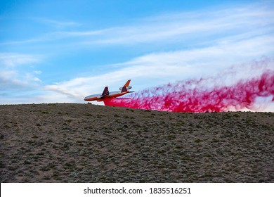 Emergency Response Airplane Drops Fire Retardant Over A Wildfire Going Behind A Desert Hill With Sagebrush