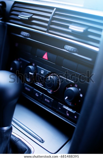 Emergency stop button with\
red tiangle sign and climate control panel modern luxury car\
interior details