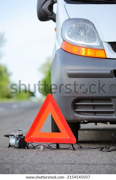 Emergency\
triangle stop sign and broken car on\
road