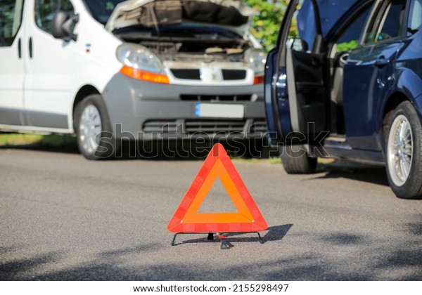 Emergency\
triangle stop sign near broken cars on\
road