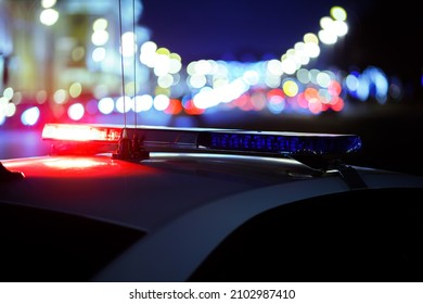 Emergency Vehicle Lighting - Police Car Roof Mounted Strobe Lightbar. Night Crime Scene. Blurred Background Wih City Lights.