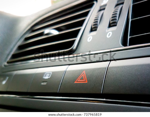 Emergency warning button with triangle\
pictogram on panel in a car. Shot from the\
angle