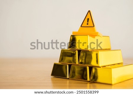 Emergency warning sign on stack gold bars with white wall background copy space. Risk management in gold commodity trading market investment, gold price falling down, global economy concept.