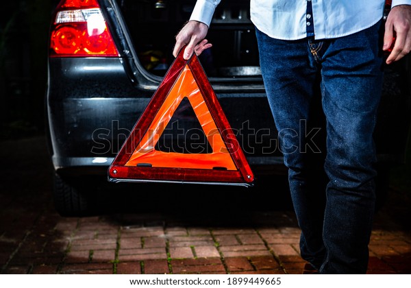 An emergency warning\
triangle in a male hand. A road accident, a car breakdown,\
emergency situation.
