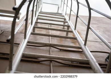 An Emergency Way Climbing Ladder With Falling Prevetion Cage At The Outside Of Factory Building. Industrail Equipment Object Photo, Selective Focus At Some Rail Step.