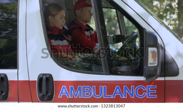 Emergency workers sitting in car, driving to\
emergency call-out, first\
aid