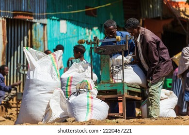 EMFRAZ, ETHIOPIA - JANUARY 17, 2022: Two Man Lifting A Heavy Sack On An Old Scale At The Market Of Emfraz Near Lake Tana.