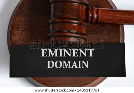 EMINENT DOMAIN - words on a black sheet against the background of a judge's gavel. Business concept