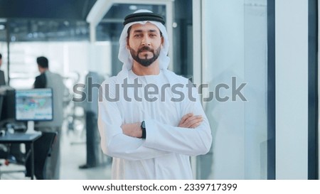 Emirati Arab at office wearing Kandura looking at front ideal for Middle East business concept. Arabic man inside a corporate establishment with colleagues at the background. Сток-фото © 