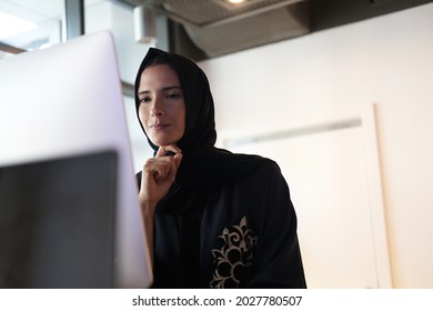 Emirati Arab woman at office using computer while working Business corporate concept of Arabic female wearing Abaya with Hijab. Natural light