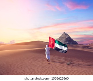 Emirati man holding UAE flag walking in the desert celebrate the national day - spirit of the union 