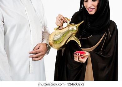 Emirati man with wife pouring coffee into cup