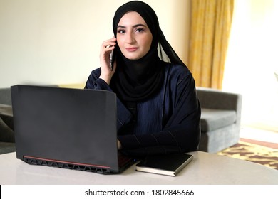 Emirati Woman On Hijab Abaya Working Remotely, Calling Her Colleuges While Staying Indoor Home. Arab Woman Communicate Through Mobile Phone. Business Or Corporate Concept