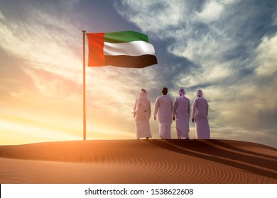 Emirati Young men standing on sand dune on the desert looking in  UAE flag celebrating national day and Uae flag day