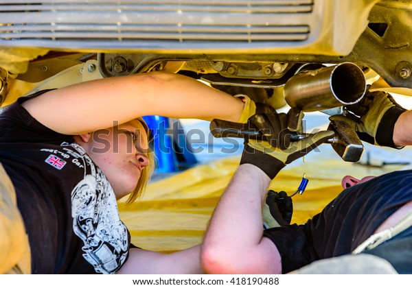 Emmaboda, Sweden - May 7, 2016: 41st\
South Swedish Rally in service depot. Crew working under the\
Mitsubishi EVO X at team Rydholm (32). Female\
mechanic.