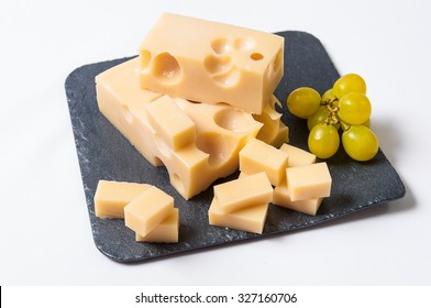 Emmental Cheese Cut And Grapes On A Slate Table