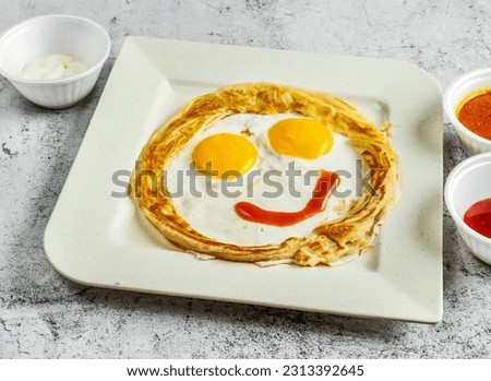 Emoji paratha with sunny egg, chilli and tomato sauce and mayo dip served in dish isolated on background top view of desi indian food