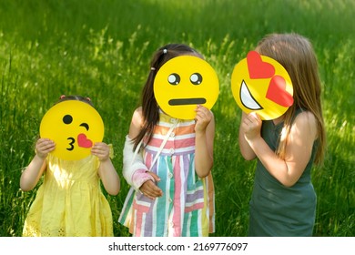 A emoticon sending an air kiss, a loving and a very sad upset smile face in the hands of children