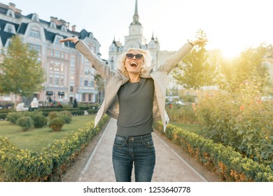 Emotion joy and happiness, young happy woman raised her hands up, outdoor background, golden hour.
