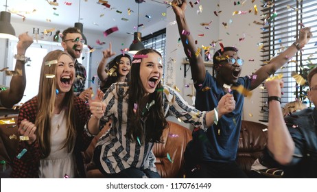 Emoção. Fãs multiétnicos comemoram a vitória. Câmera lenta confete 4K. Apoiadores apaixonados gritam assistindo jogo na TV.