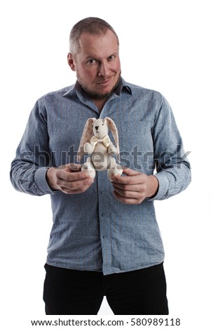 emotional actor man in a gray shirt with a soft toy bunny in hand, on a white background in studio