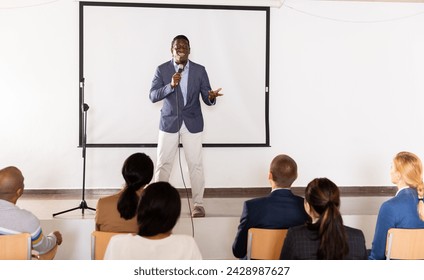 Emotional aframerican business coach giving motivational training for group of businesspeople, speaking from stage in conference room - Powered by Shutterstock