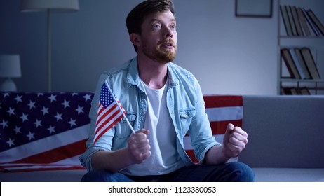 Emotional American Man Holding USA Flag And Watching Election Results On Tv Home