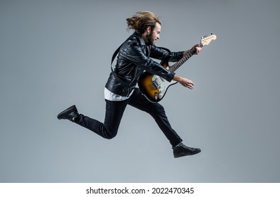 emotional bearded rock musician playing electric guitar in leather jacket and jumping, music - Powered by Shutterstock