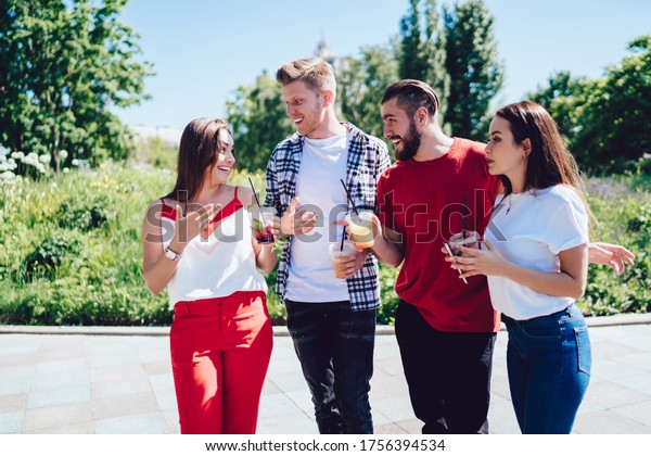 Emotional best friends discussing taste of\
cold cocktails enjoying double date for communicate and flirting,\
joyful hipster guys satisfied with sincerely conversation during\
touristic travelling