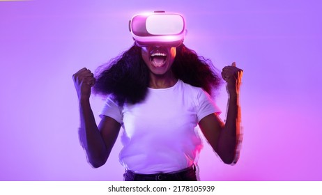 Emotional black lady in VR glasses exploring cyberspace, shouting in excitement, raising fists up, playing virtual reality game in neon light, experiencing modern technologies, collage - Powered by Shutterstock