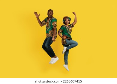 Emotional black man and woman in traditional african clothing celebrating success together on yellow studio background, couple jumping in the air and gesturing, full length shot - Powered by Shutterstock