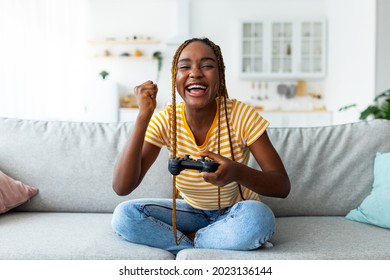 Emotional Black Woman Playing Video Game With Joystick At Home, Copy Space. Happy Millennial African American Lady Enjoying Weekend, Sitting On Couch In Living Room With Joystick, Gaming