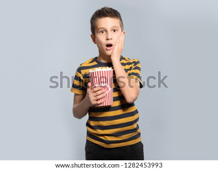 Similar – surprised boy with popcorn and television remote control on blue background