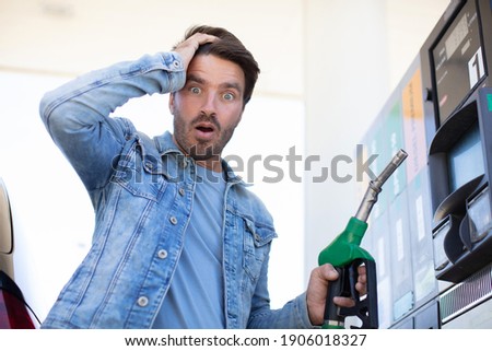 emotional businessman counting money with gasoline refueling car