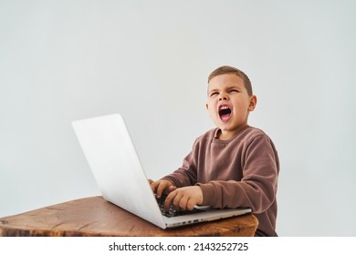 Emotional Child With Laptop Shout. Gambling Addiction. Handsome Child Gamer Play Online Games On Laptop On White Background