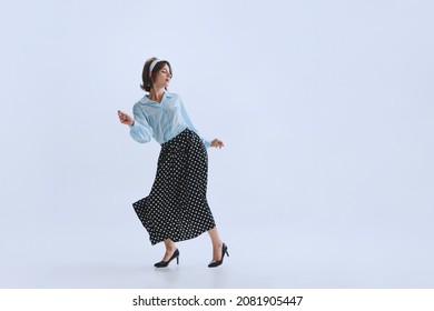 Emotional dance. Portrait of emotional young woman in retro style clothes, vintage outfit dancing rock-and-roll isolated on white background. Concept of culture, art, music, fashion style, ad - Shutterstock ID 2081905447