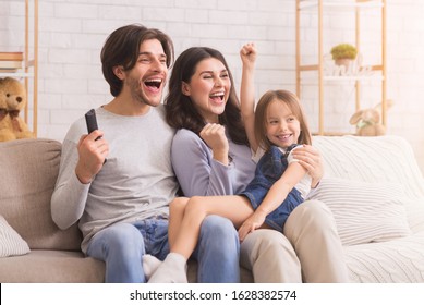 Emotional Family Cheering Sports Together, Watching Football Game On Tv, Celebrating Victory While Sitting On Sofa At Home