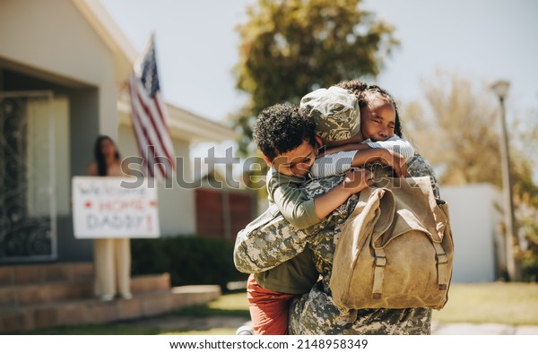Emotional\
family reunion. Military dad embracing his children after returning\
home from the army. American soldier receiving a warm welcome from\
his family after serving in the\
military.