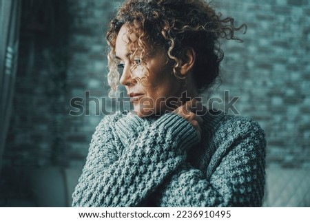Emotional feeling portrait of woman hugging herself with love and protection concept. Serene and intimate adult female people embracing her body and neck looking on her side outside the window