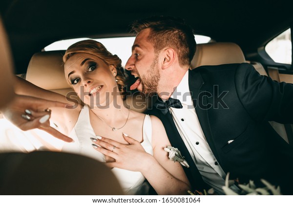 Emotional funny\
happy married couple singing and squirming in the car. The brides\
is young, blonde and\
brunette