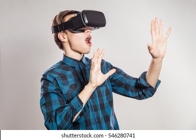 Emotional Funny Man Wearing Virtual Reality Goggles. Studio Portrait Of Video Game Designer Wearing VR Headset. Studio Shot Isolated On Gray Background.