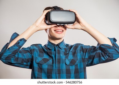 Emotional Funny Man Wearing Virtual Reality Goggles. Studio Portrait Of Video Game Designer Wearing VR Headset. Studio Shot Isolated On Gray Background.